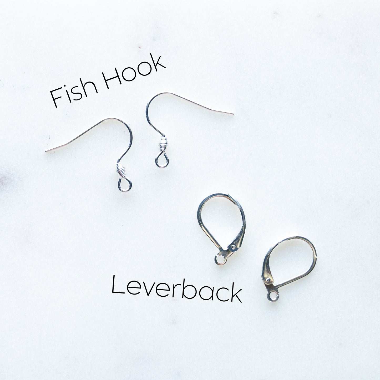 Two pairs of silver earring hardware on a white background: fish hooks at the top and leverbacks at the bottom, with black text labels reading 'Fish Hook' and 'Leverback'.